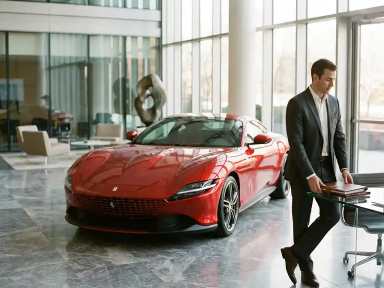Rode Ferrari sportwagen in moderne kantoorlobby met zakenman die leasecontracten bekijkt aan glazen bureau