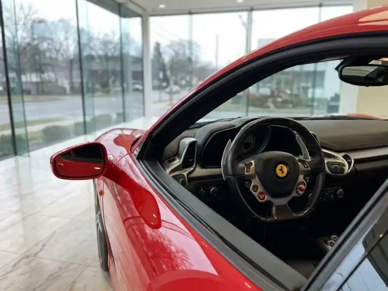 Rode Ferrari sportwagen in moderne showroom met verlichte stuurwielknoppen en marmeren vloer