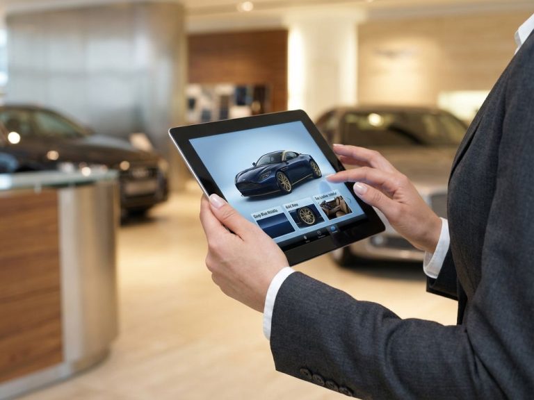 Handen in pak houden tablet met luxe supercar configurator in premium autoshowroom met exotische sportwagens
