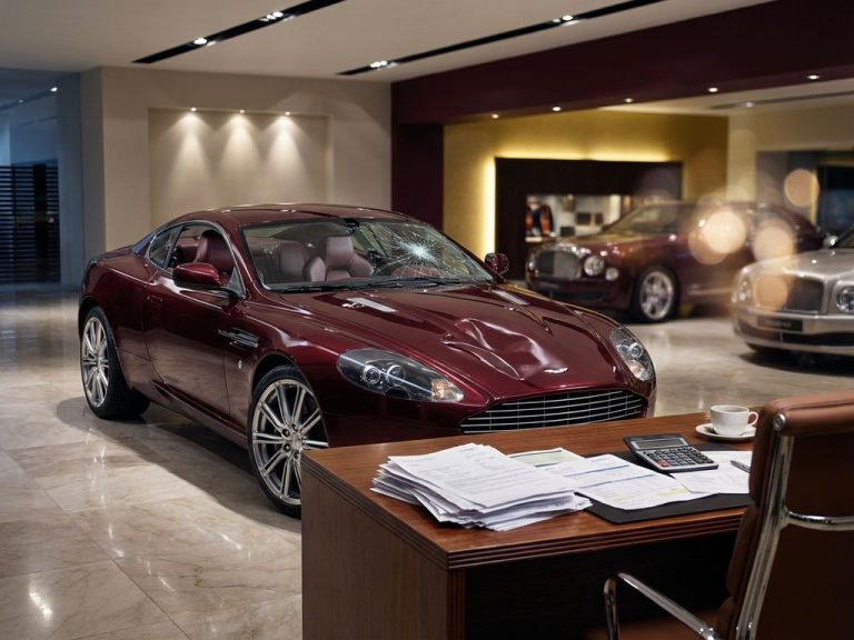 Beschadigde luxe supercar met gebarsten voorruit en gedeukte motorkap in chique showroom met verzekeringspapieren