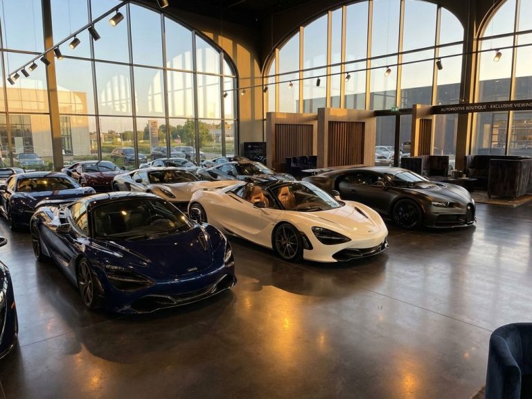 Luxe autoshowroom met supercars in middernachtblauw, parelwit en zwart onder dramatische verlichting op glanzende vloeren