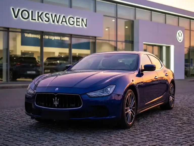 Maserati Ghibli sportwagen geparkeerd voor Volkswagen dealer showroom met warme avondverlichting