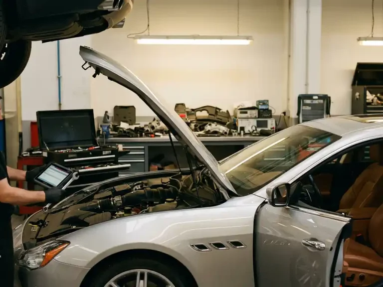 Zilveren Maserati sedan in moderne garage met monteur die motor inspecteert met professionele gereedschappen