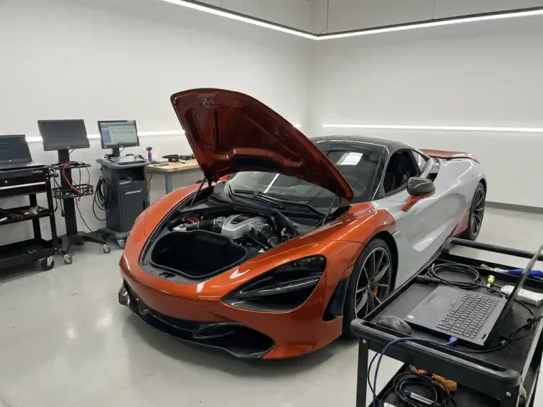 McLaren 720S met geopende motorkap toont twin-turbo V8 motor in witte servicewerkplaats met diagnostische apparatuur