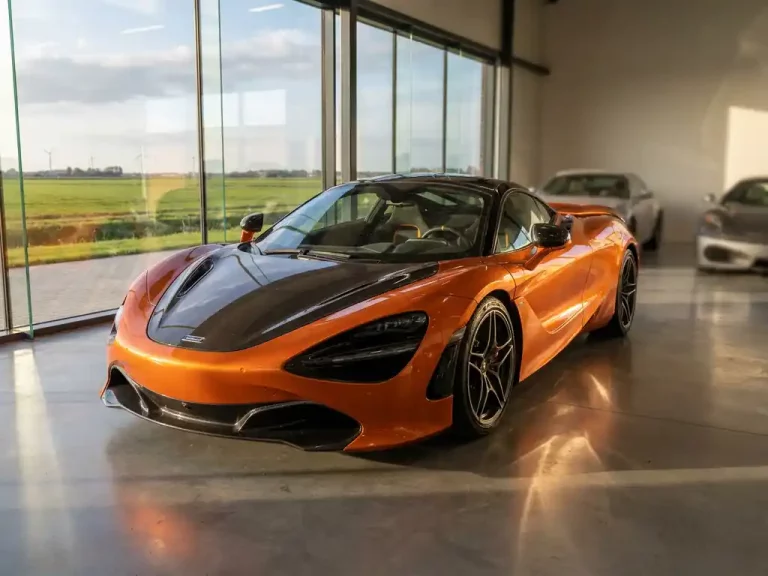 McLaren 720S in Papaya Orange getoond in moderne showroom met Nederlandse landschap op achtergrond