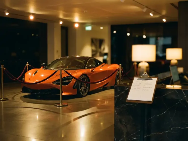 McLaren 720S in papaya oranje achter fluwelen afzettingskoordje in exclusieve showroom met dramatische verlichting