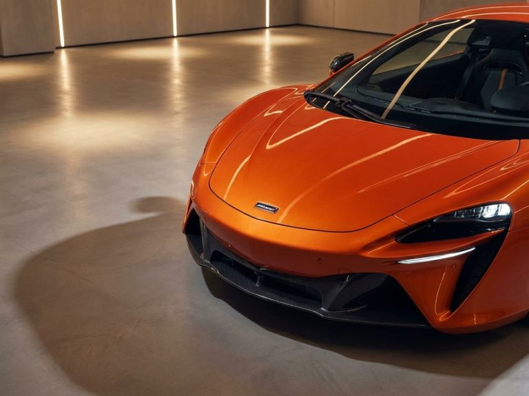 Oranje McLaren supercar vooraanzicht in moderne showroom met LED-verlichting en gepolijste betonnen vloeren