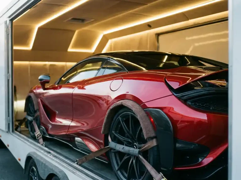 Rode McLaren supercar vastgebonden in professionele autotransporter met LED-verlichting en beschermende padding