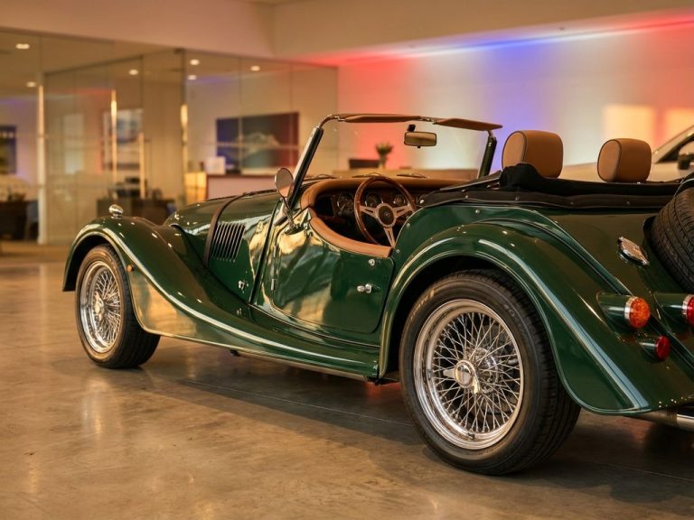 Groene Morgan sportwagen in showroom met draadwielen en leren interieur, dramatische studiobelichting