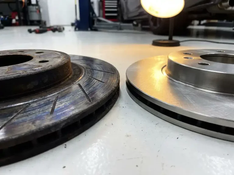 Versleten remschijf met krassen en verkleuring naast nieuwe remschijf in luxe autowerkplaats